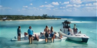 Guests standing on a sandbar beside the boat Guests standing on a sandbar beside the boat